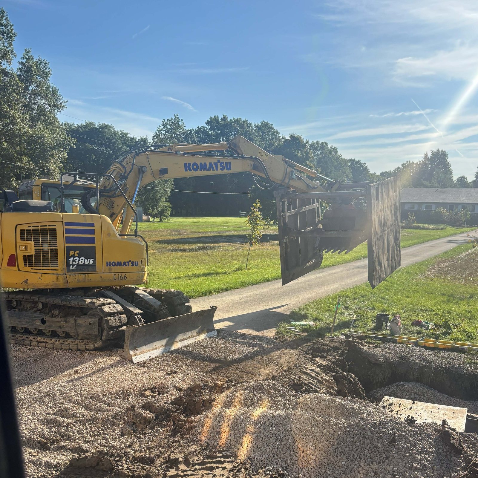Trench shield hanging from an excavator boom mid-set