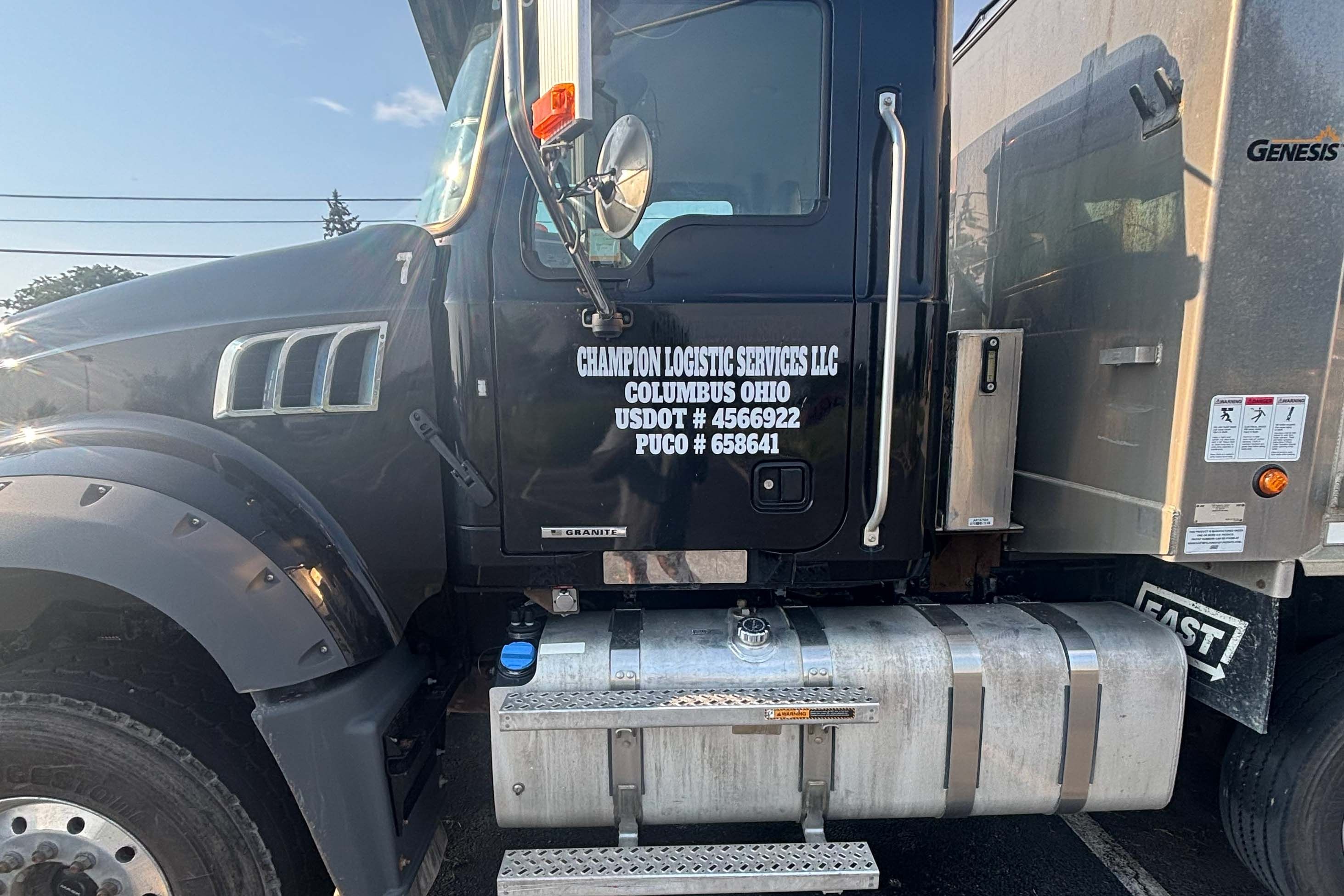 A black Champion dump truck with its lettered door on a job street