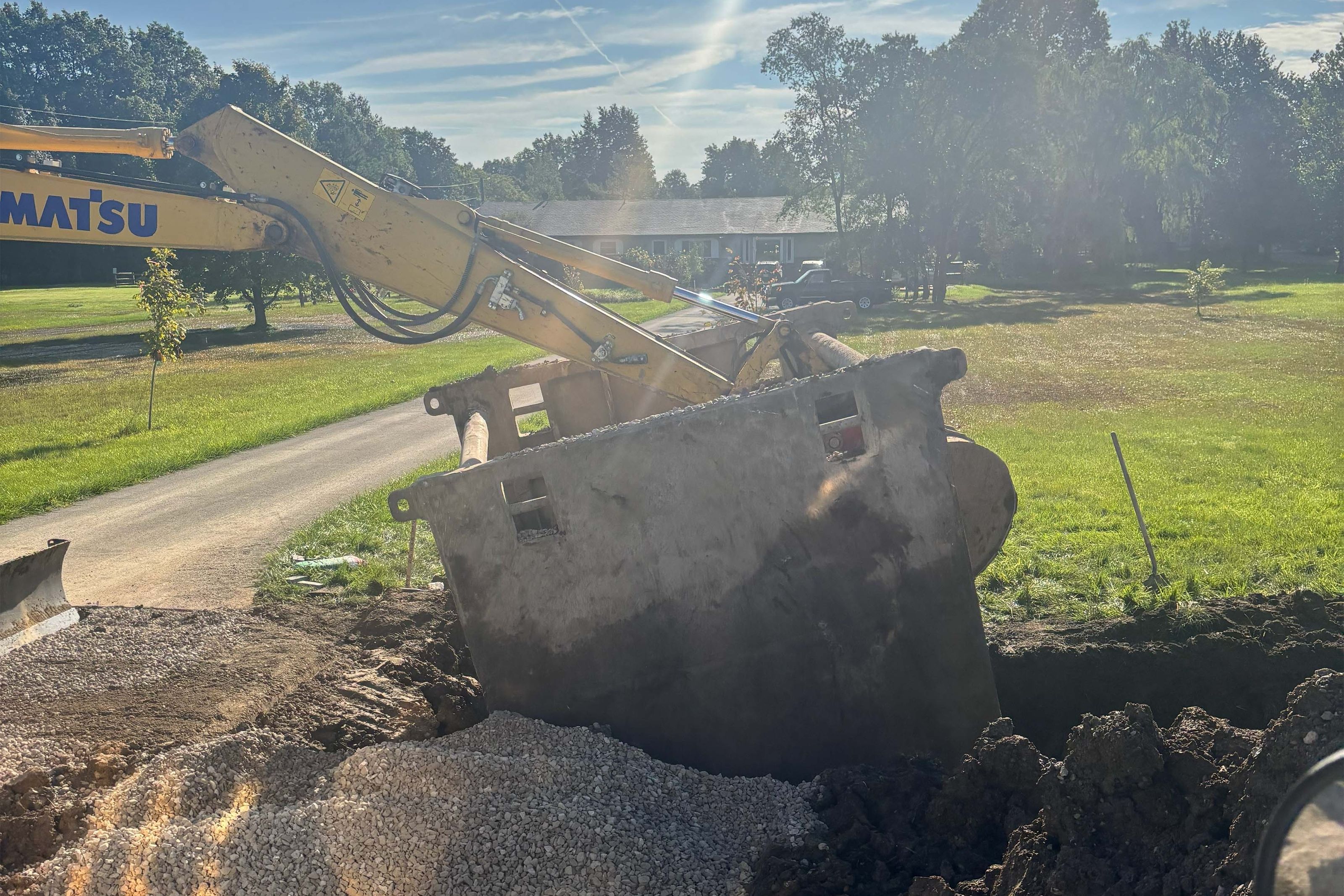 Excavator lowering a concrete vault onto a fresh gravel base